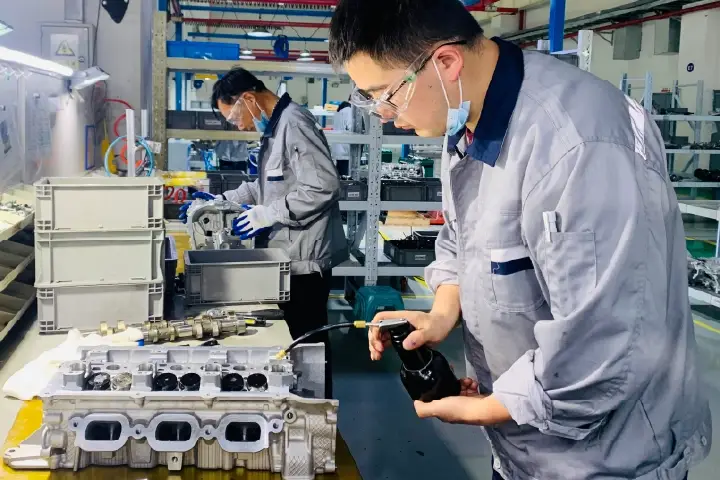 ATC reman factory floor - worker in China remanufacturing plant cleaning an ICE automobile engine.